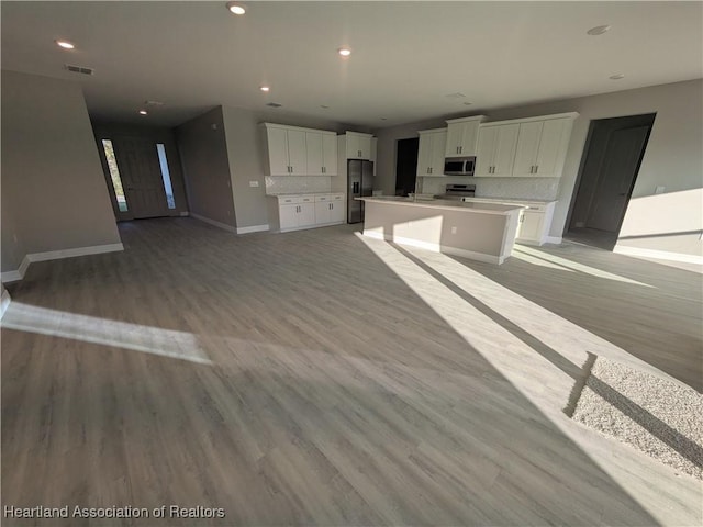 kitchen featuring decorative backsplash, white cabinetry, stainless steel appliances, and a kitchen island