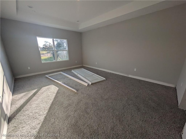 carpeted empty room featuring a tray ceiling