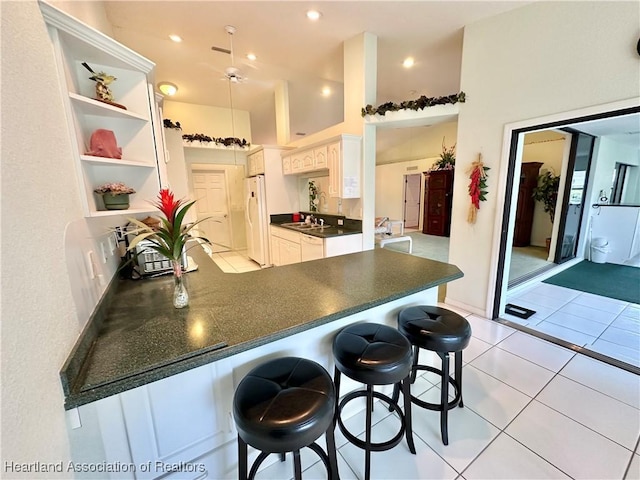 kitchen featuring white cabinetry, a kitchen breakfast bar, built in features, white refrigerator, and kitchen peninsula