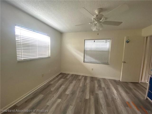 spare room with a textured ceiling, dark wood-style flooring, and a healthy amount of sunlight