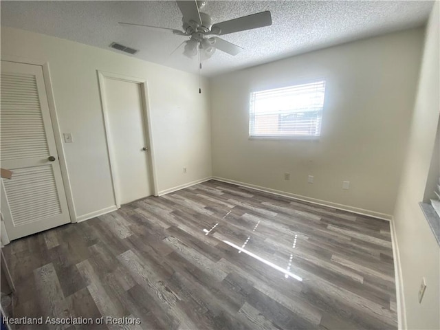 unfurnished bedroom with dark wood-style flooring, visible vents, ceiling fan, a textured ceiling, and baseboards