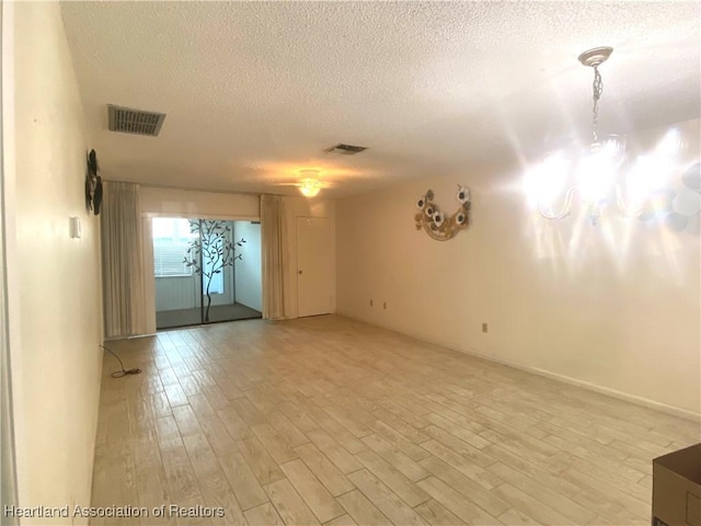 unfurnished room featuring a textured ceiling and light hardwood / wood-style floors