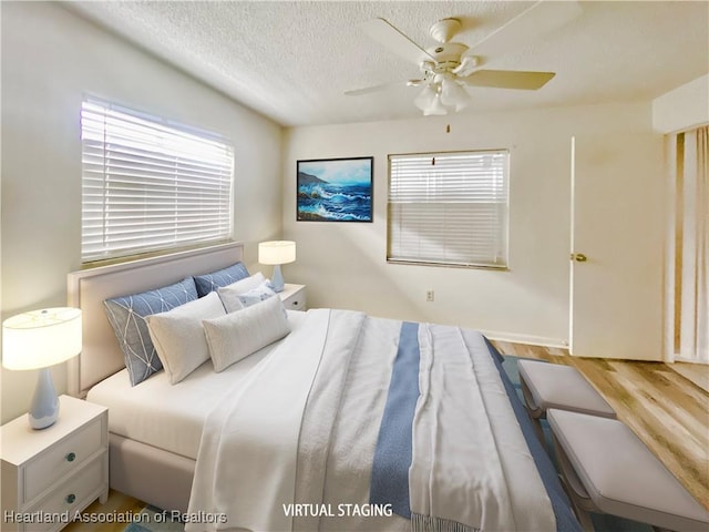 bedroom with ceiling fan, multiple windows, a textured ceiling, and wood finished floors