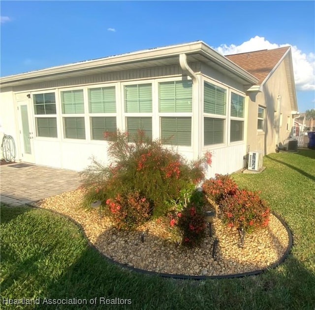 view of side of home with ac unit, a yard, a patio area, central AC, and stucco siding