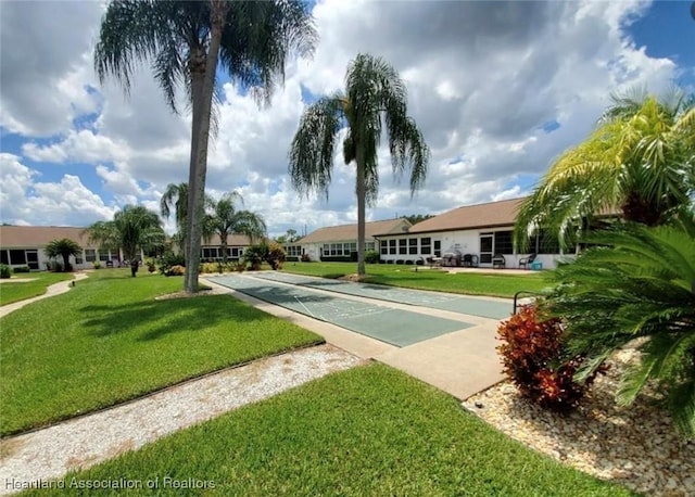 view of property's community featuring a lawn and shuffleboard