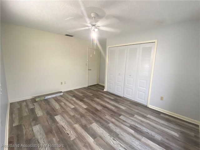 unfurnished bedroom featuring dark hardwood / wood-style flooring, a textured ceiling, a closet, and ceiling fan