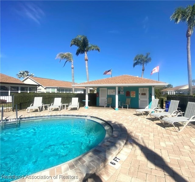 pool with a patio area and fence