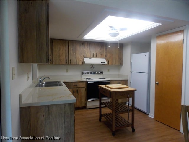 kitchen featuring white appliances, a skylight, sink, and hardwood / wood-style floors