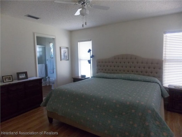 bedroom featuring ceiling fan, hardwood / wood-style floors, a textured ceiling, and ensuite bath