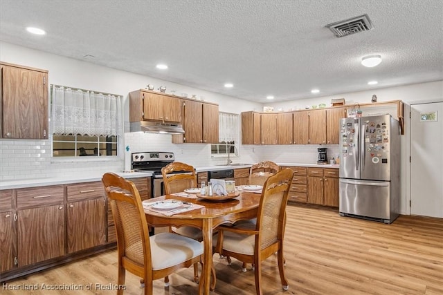 kitchen with light hardwood / wood-style floors, stainless steel appliances, and backsplash