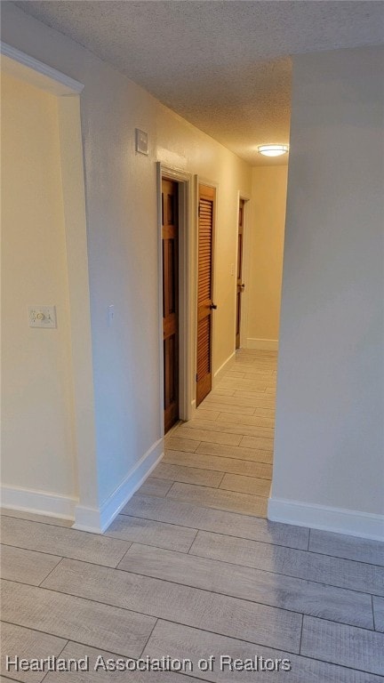 hall with light hardwood / wood-style flooring and a textured ceiling