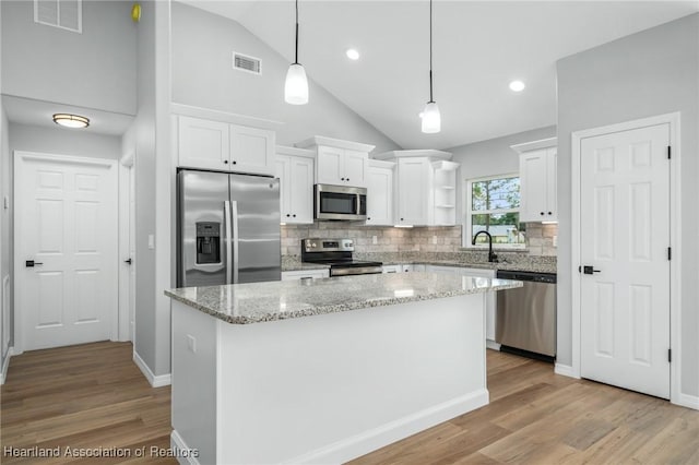 4225 Cooper Dr, Sebring, FL 33872 - kitchen featuring appliances with stainless steel finishes, open shelves, lofted ceiling, white cabinets, and tasteful backsplash