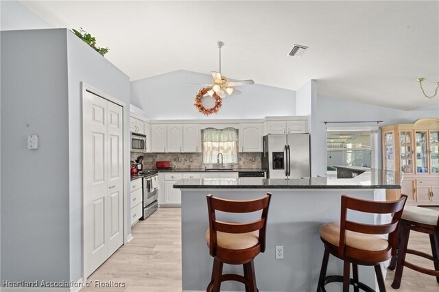 3730 Camry Ct, Sebring, FL 33872 - kitchen featuring appliances with stainless steel finishes, lofted ceiling, a kitchen bar, backsplash, and a ceiling fan