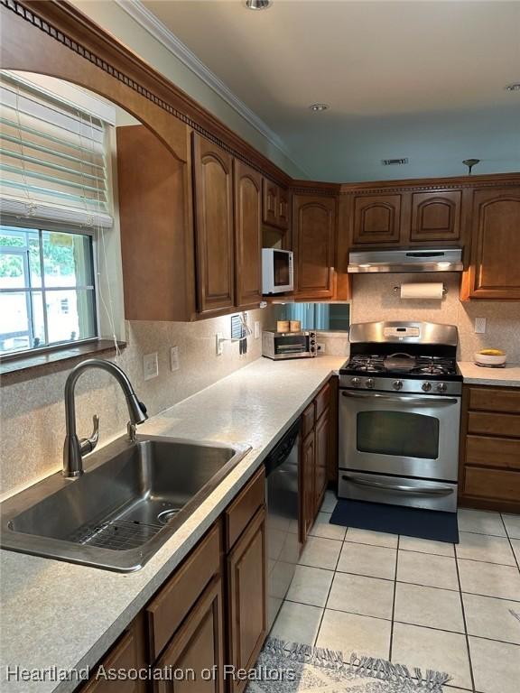 kitchen featuring decorative backsplash, appliances with stainless steel finishes, crown molding, sink, and light tile patterned floors