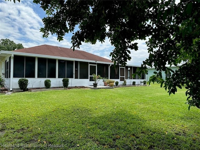 rear view of house featuring a sunroom and a lawn