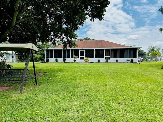 back of property with a lawn and a sunroom