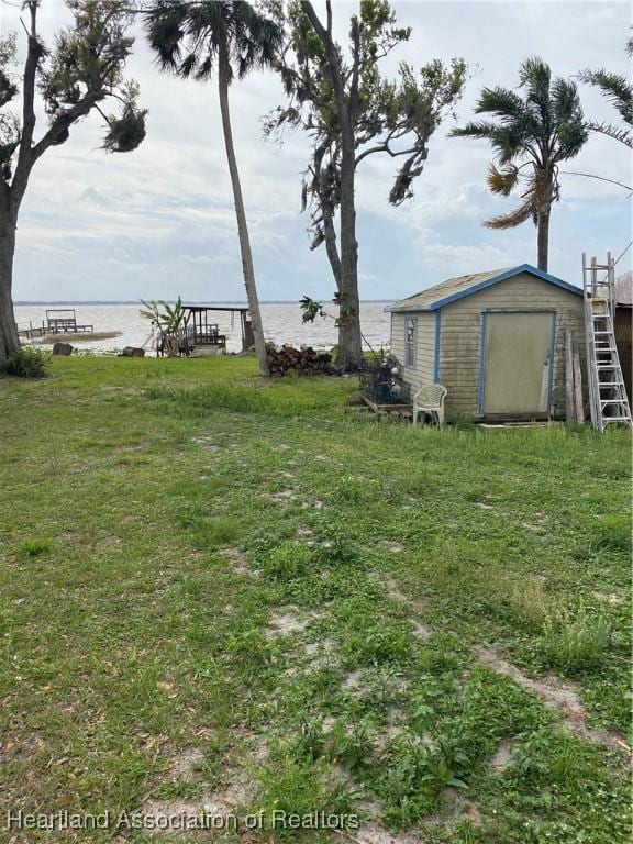 view of yard featuring a shed, an outdoor structure, and a water view