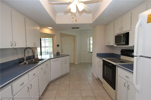 kitchen with white appliances, white cabinets, sink, light tile patterned floors, and a tray ceiling