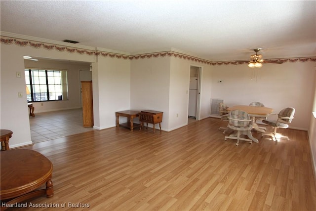 dining area featuring ceiling fan, light hardwood / wood-style floors, and a textured ceiling