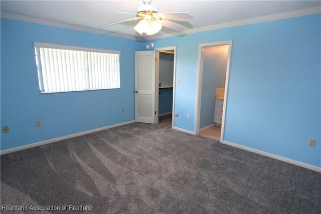 unfurnished bedroom with a walk in closet, ensuite bathroom, ceiling fan, crown molding, and carpet floors