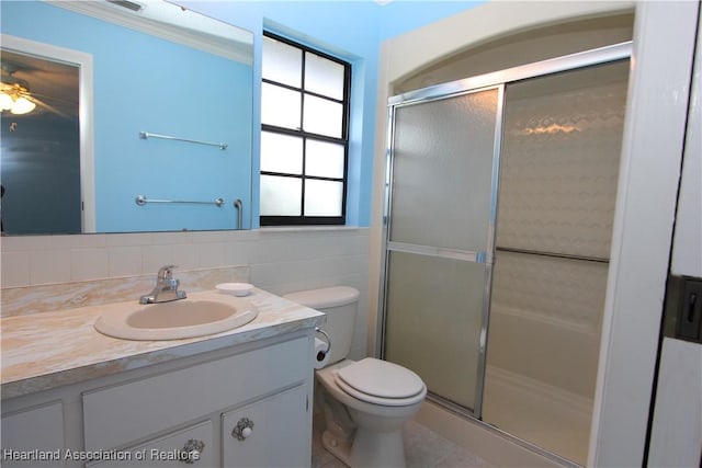 bathroom with ceiling fan, toilet, a shower with door, and tile walls