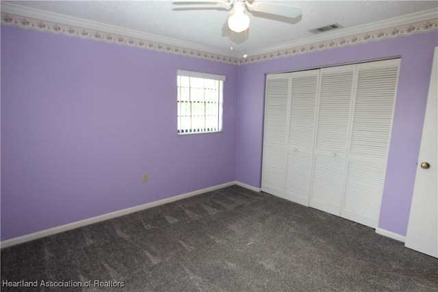 unfurnished bedroom featuring dark colored carpet, ceiling fan, crown molding, and a closet