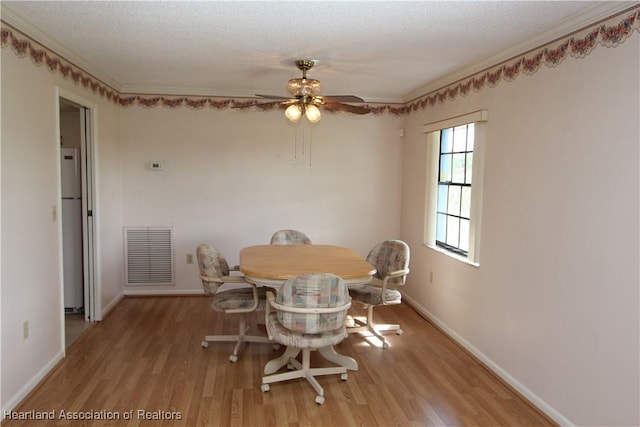 dining area with a textured ceiling, light hardwood / wood-style floors, ceiling fan, and crown molding