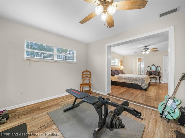 bedroom with wood finished floors, visible vents, baseboards, and multiple windows