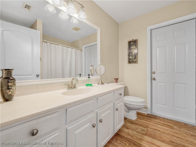 bathroom featuring toilet, visible vents, wood finished floors, and vanity