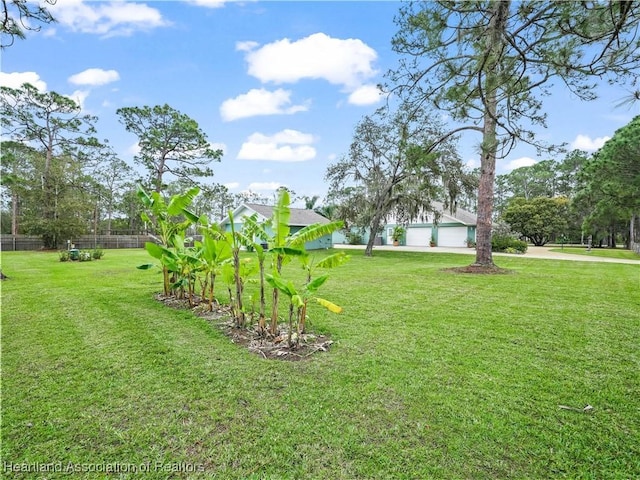 view of yard with a garage, driveway, and fence