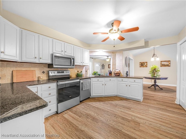 kitchen with stainless steel appliances, light wood-style floors, white cabinetry, a sink, and a peninsula