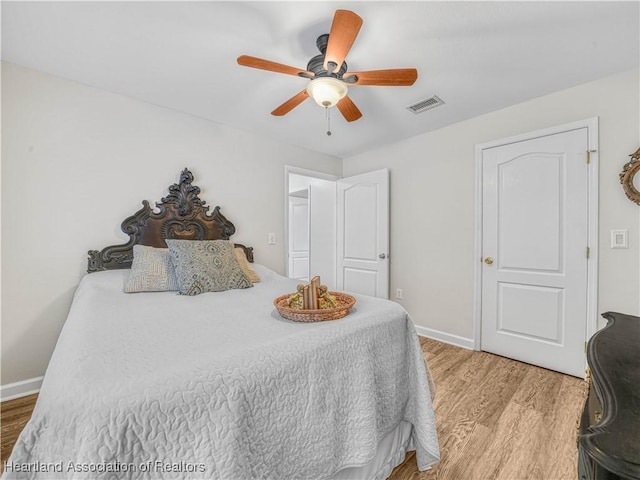 bedroom featuring visible vents, ceiling fan, baseboards, and wood finished floors