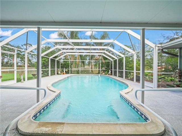 outdoor pool with glass enclosure and a patio area