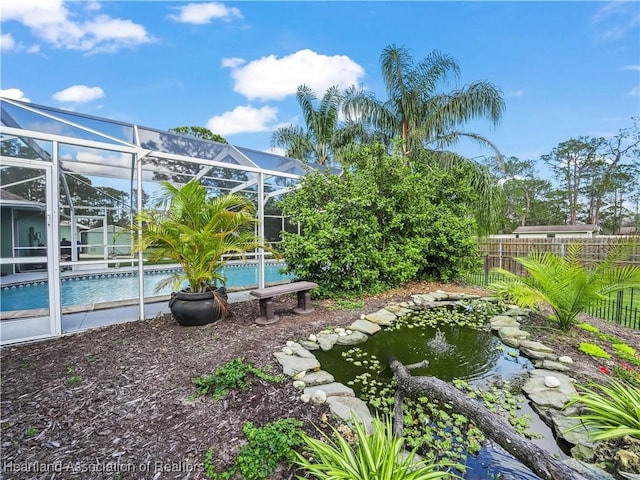 view of yard with an outdoor pool, glass enclosure, and fence