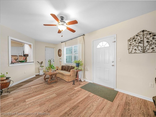 foyer featuring light wood-type flooring, ceiling fan, and baseboards