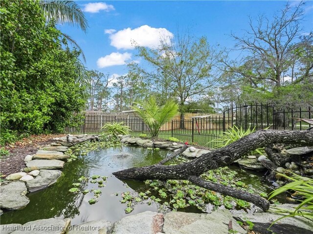 view of yard with fence and a small pond