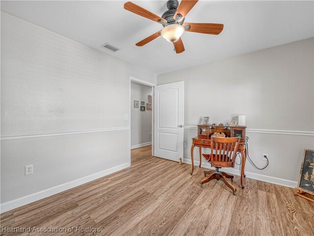 living area featuring a ceiling fan, wood finished floors, visible vents, and baseboards