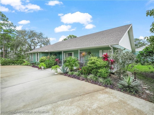 ranch-style house featuring covered porch, roof with shingles, and stucco siding