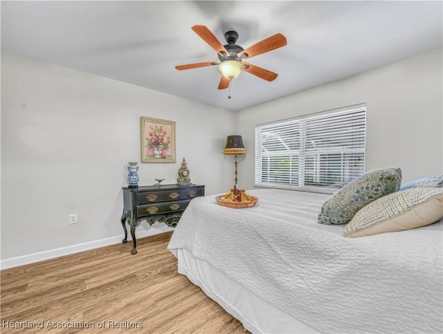 bedroom featuring a ceiling fan, baseboards, and wood finished floors