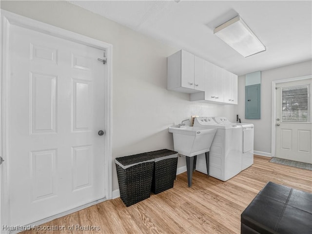 clothes washing area with light wood-type flooring, separate washer and dryer, cabinet space, and electric panel