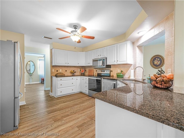 kitchen featuring stainless steel appliances, visible vents, backsplash, a sink, and light wood-type flooring