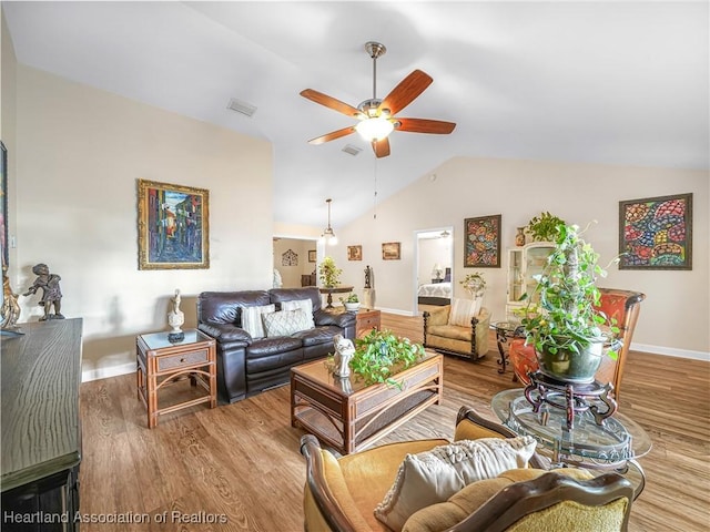 living area with lofted ceiling, wood finished floors, visible vents, a ceiling fan, and baseboards