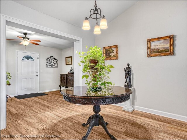 entryway with ceiling fan with notable chandelier, light wood-style flooring, and baseboards