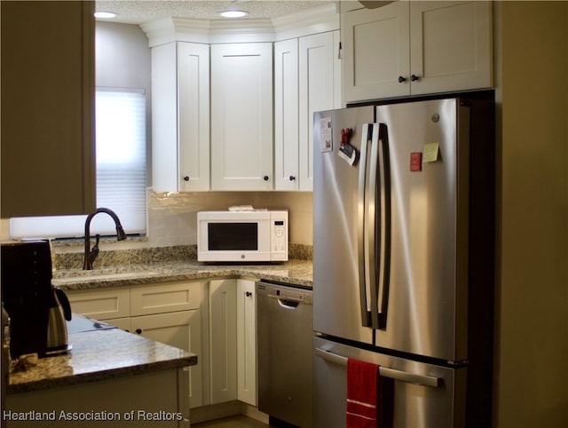 102 Oak St, Lake Placid, FL 33852 - kitchen with stainless steel appliances, a sink, white cabinetry, a textured ceiling, and light stone countertops