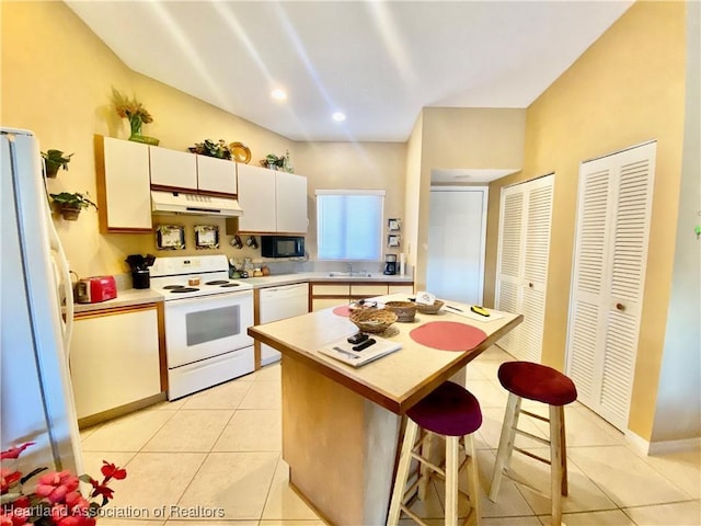 4869 Casablanca Cir Unit G22, Sebring, FL 33870 - kitchen with white appliances, under cabinet range hood, light countertops, a breakfast bar, and light tile patterned flooring