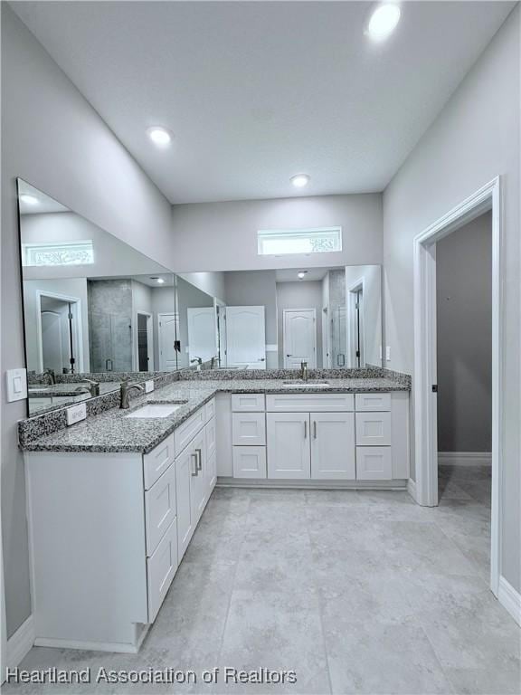 bathroom with baseboards, vanity, recessed lighting, and a shower