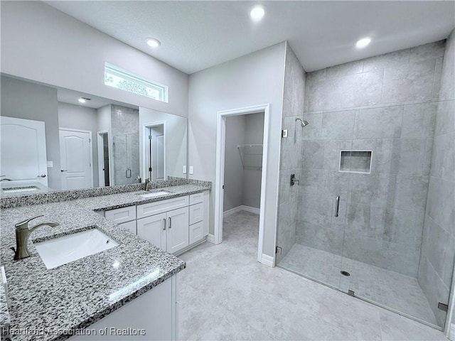 bathroom featuring a stall shower, vanity, baseboards, a spacious closet, and recessed lighting