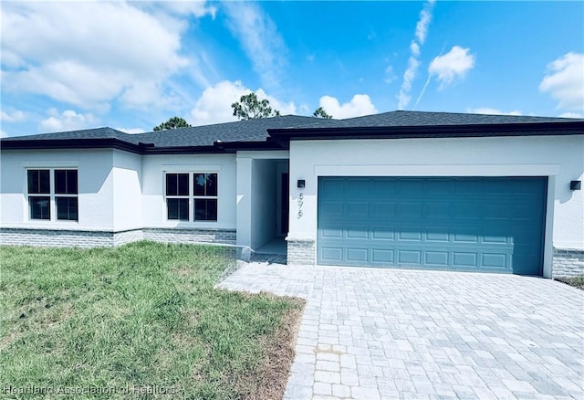 view of front of property featuring stucco siding, decorative driveway, a garage, and a front lawn