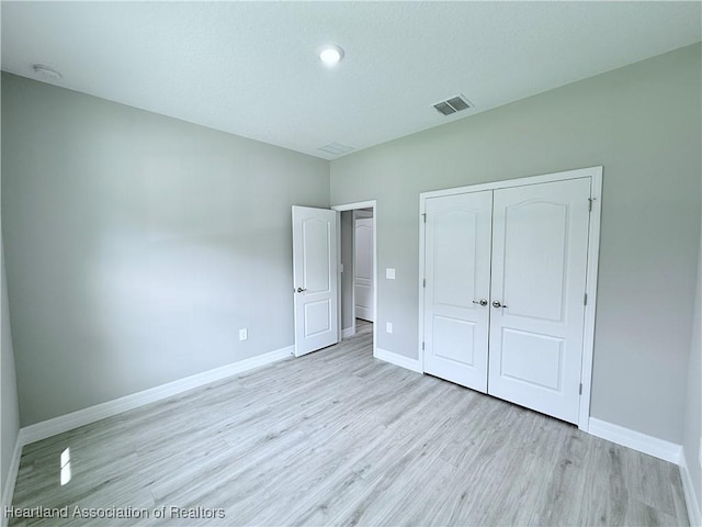 unfurnished bedroom with light wood-style floors, baseboards, and a closet