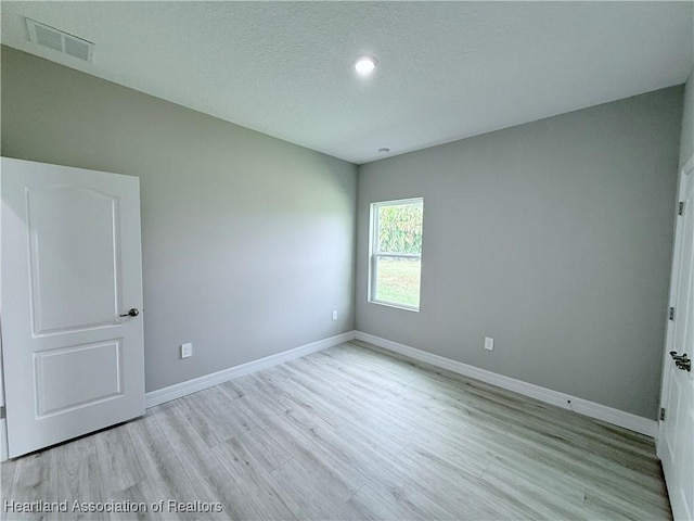 spare room with wood finished floors, baseboards, a textured ceiling, and recessed lighting